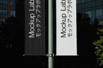 Dark black plus white vertical banners on metal pole displaying Mockup Lab copy side by side