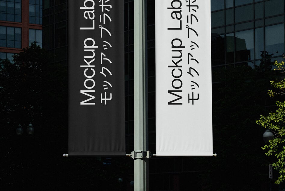 Dark black plus white vertical banners on metal pole displaying Mockup Lab copy side by side