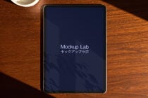 Tablet mockup featuring the Mockup Lab logo on a wooden desk with shadow play perfect for digital asset designers seeking sleek presentation tools