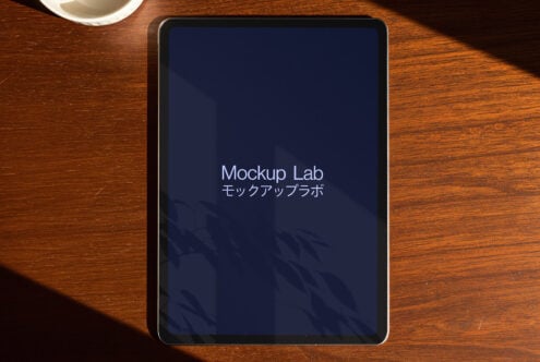 Tablet mockup featuring the Mockup Lab logo on a wooden desk with shadow play perfect for digital asset designers seeking sleek presentation tools