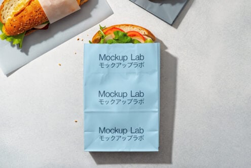Paper bag mockup with sandwich partially visible, featuring a blue design. Ideal for showcasing branding, packaging design. Perfect for designers.