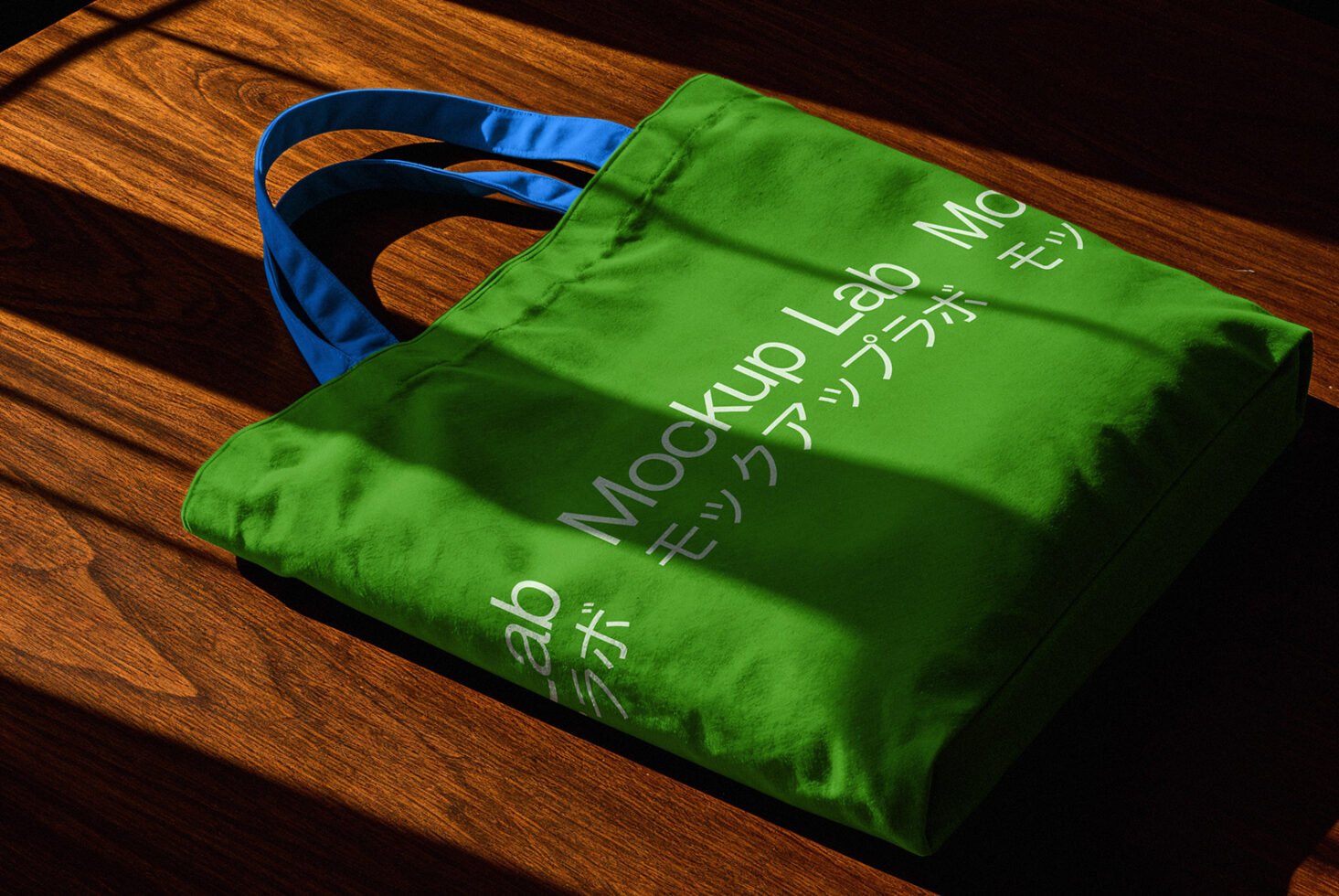 Green tote bag on wooden surface in sunlight, with white text in English and Japanese. Perfect for branding and mockup design projects.
