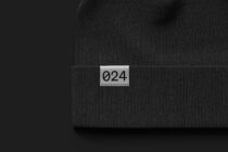 Dark charcoal ribbed beanie with numbered label sewn onto folded cuff