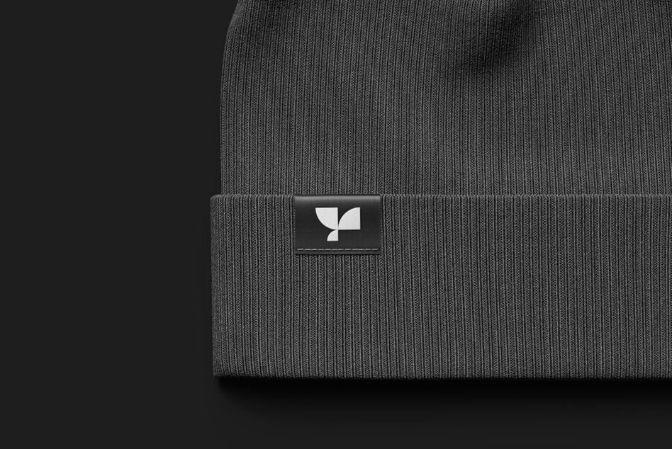 Gray ribbed beanie cap with small geometric logo label on cuff