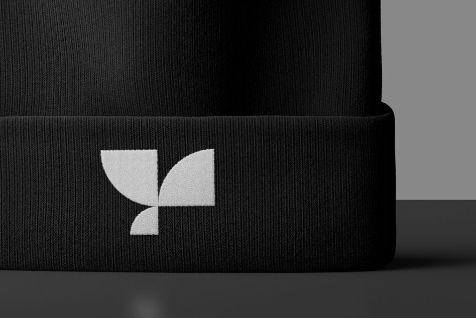 Close-up of black ribbed beanie cuff showing white geometric leaf emblem