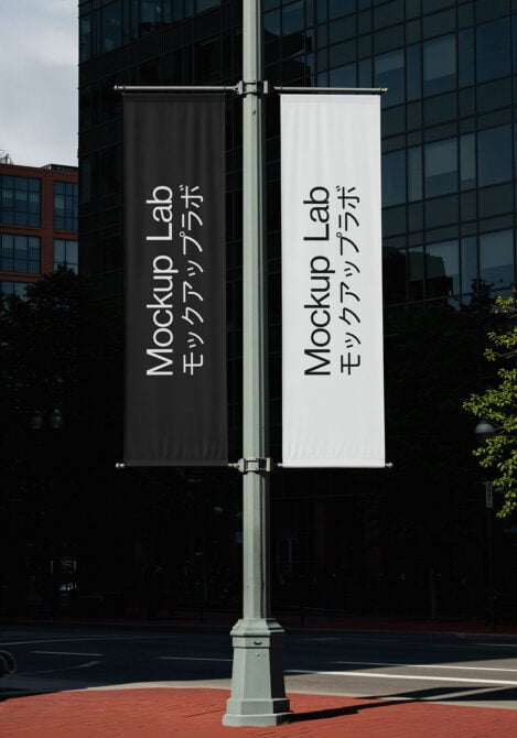 Two vertical street banners on pole, one black one white, both displaying Mockup Lab text vertically