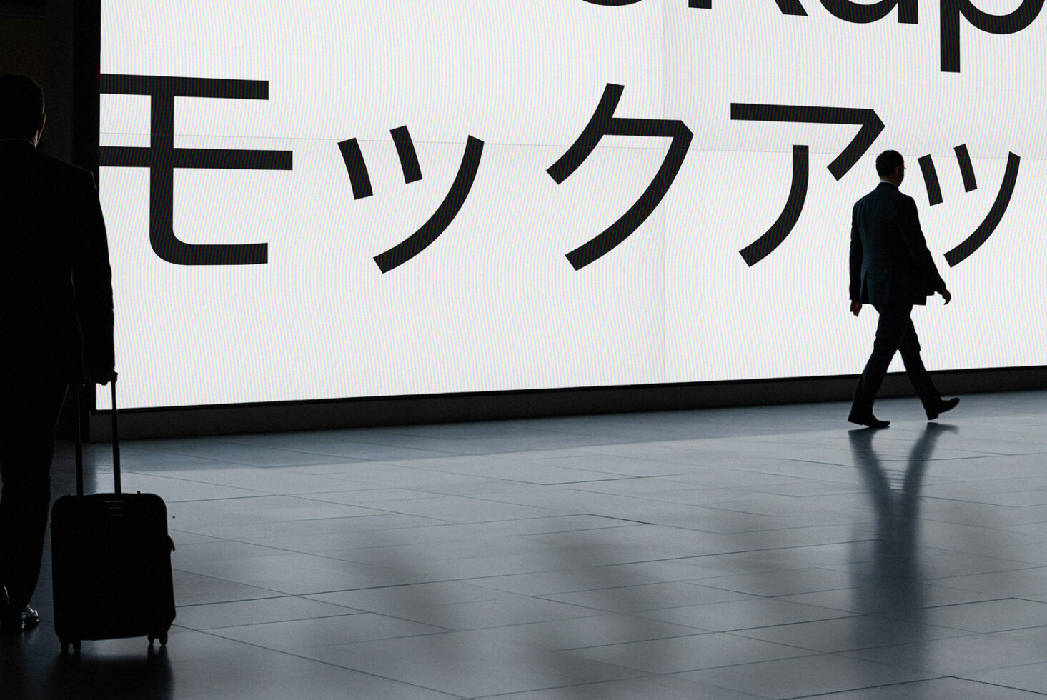 Person walking past large screen displaying Japanese katakana characters with scan lines
