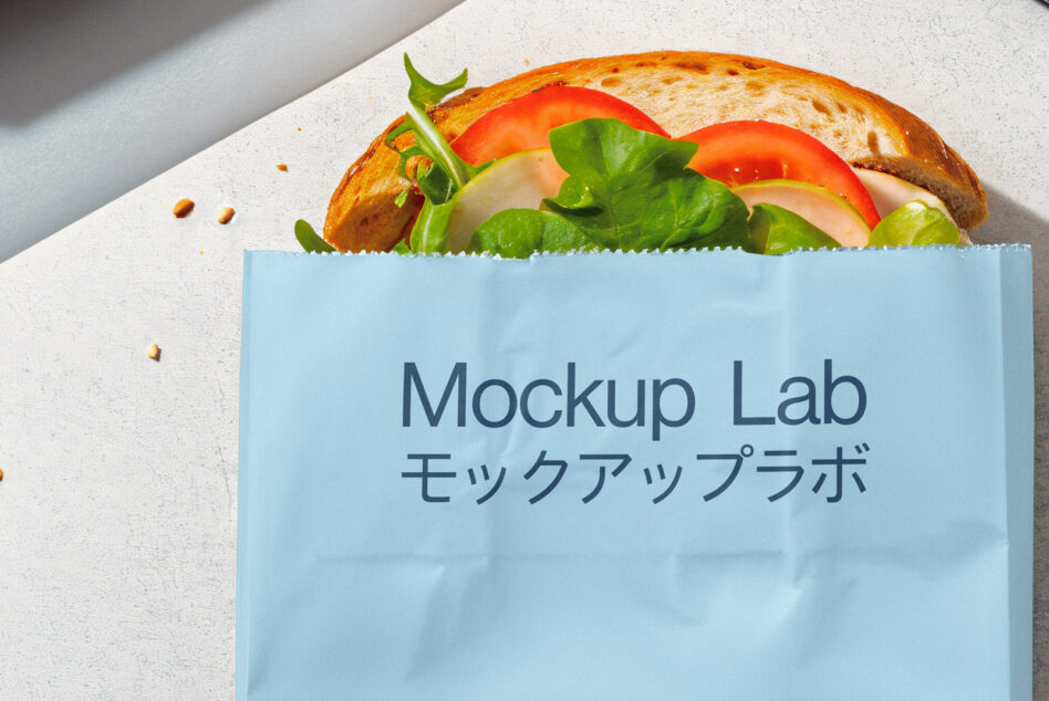 Blue paper food wrapper holding fresh sandwich with tomato, lettuce, cheese