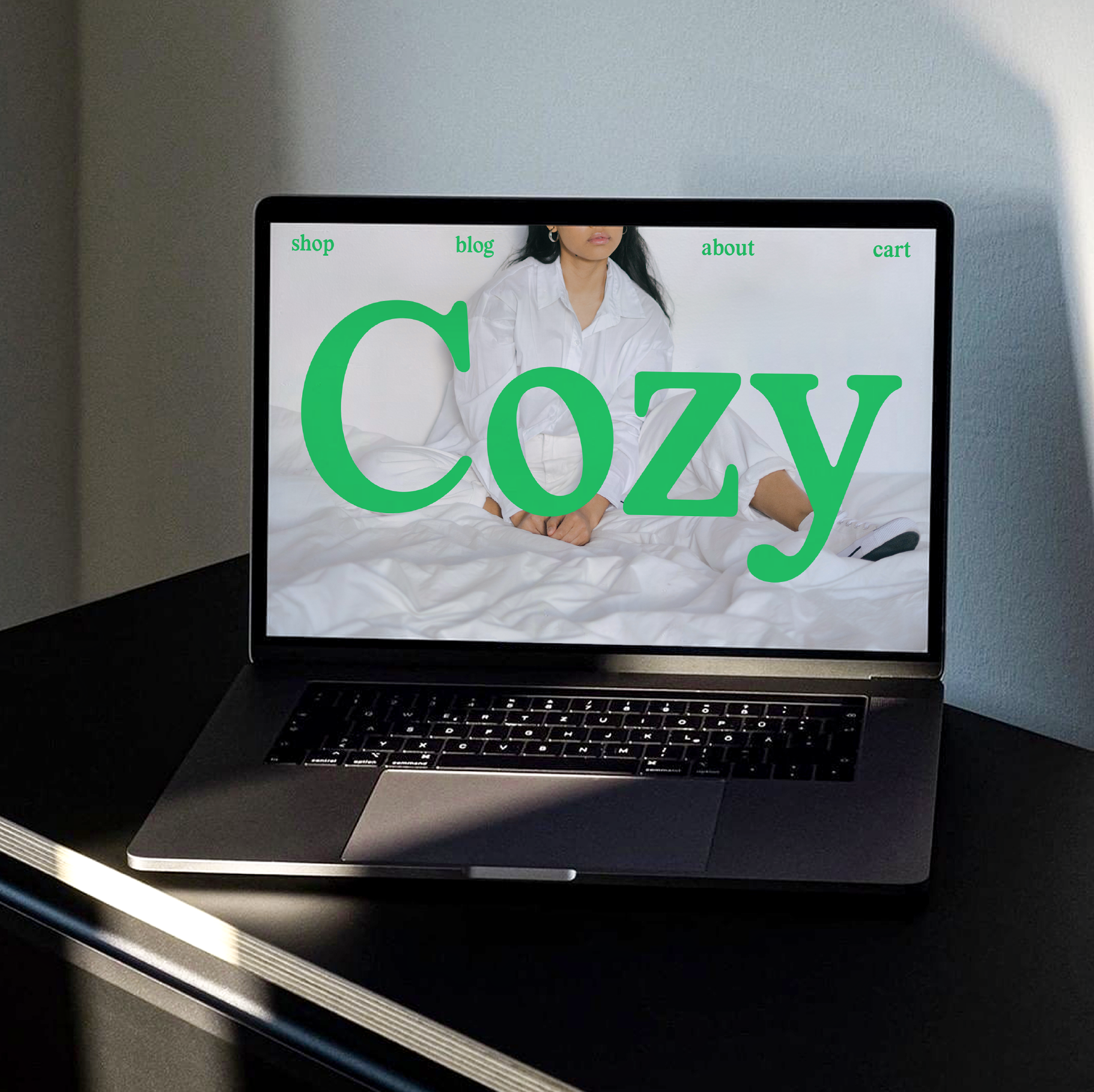 Laptop displaying a Cozy-themed website with green text on a bed image. Ideal for designers seeking creative web templates and graphic design inspiration.