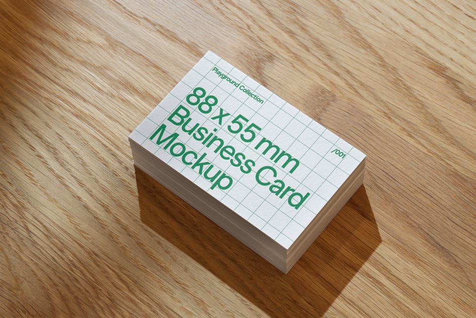 Stack of white business cards on wood showing green text layout mockup