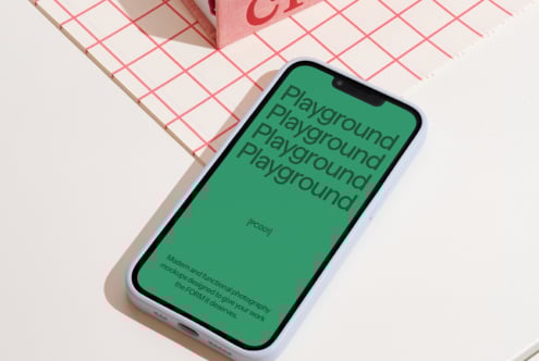 Modern smartphone mockup with green screen displaying bold text Playground. Minimalist notebook with red grid pattern. Perfect for graphic design projects.