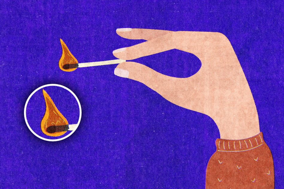 Hand holding lit match against deep blue background