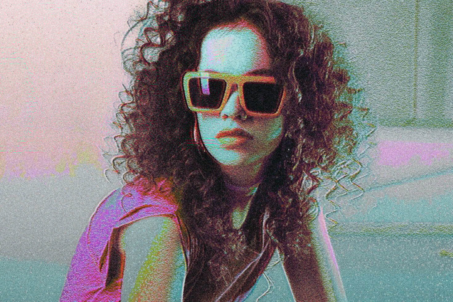 Retro-inspired image of a person with curly hair wearing oversized square sunglasses, emphasizing 80s style and grainy texture, ideal for graphic designers.
