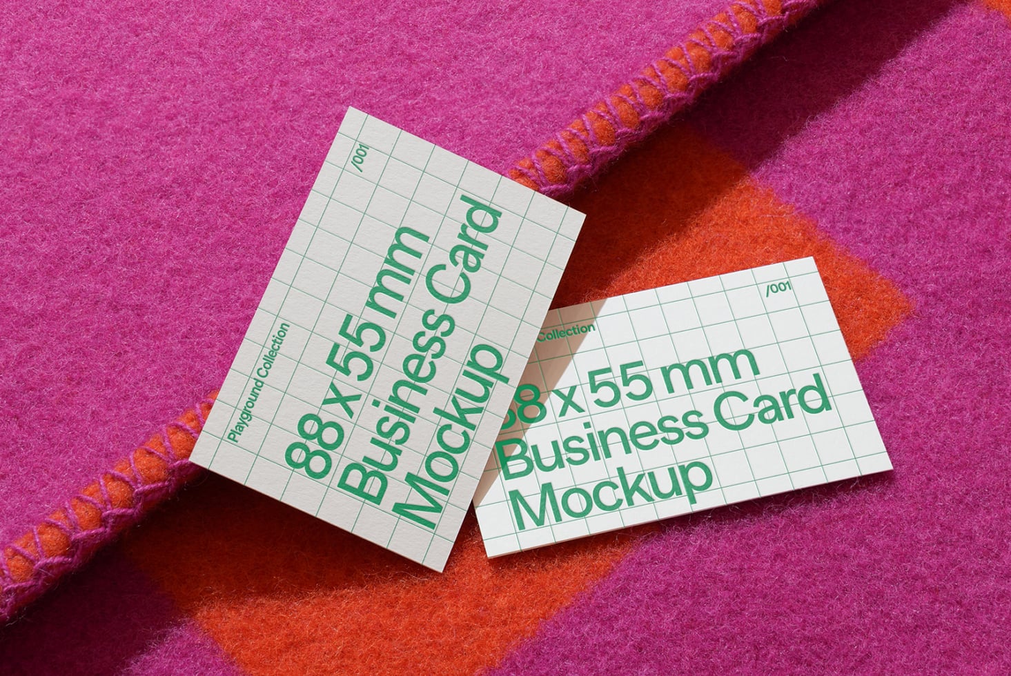 Two white business cards with green text on bright pink fabric background