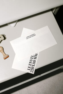 Flat lay of white seal flap envelope mockup beside wooden stamp on white desk