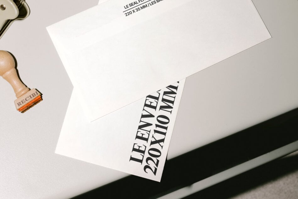White envelope with black text stamp showing dimensions, wood handle stamp nearby