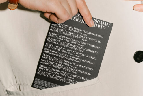 Fabric label in multiple languages held by a hand, ideal for graphic design projects, textile mockups, typography designs, or template creation.