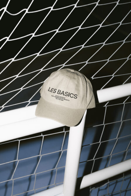 Cream cap with Les Basics branding on white mesh sports net backdrop