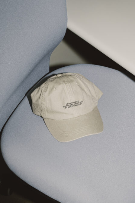 Cream colored baseball cap with embroidered text on blue sculptural surface