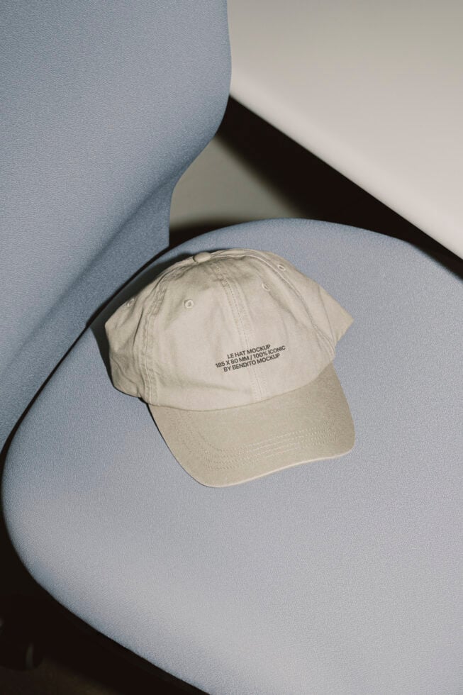 Cream colored baseball cap with embroidered text on blue sculptural surface