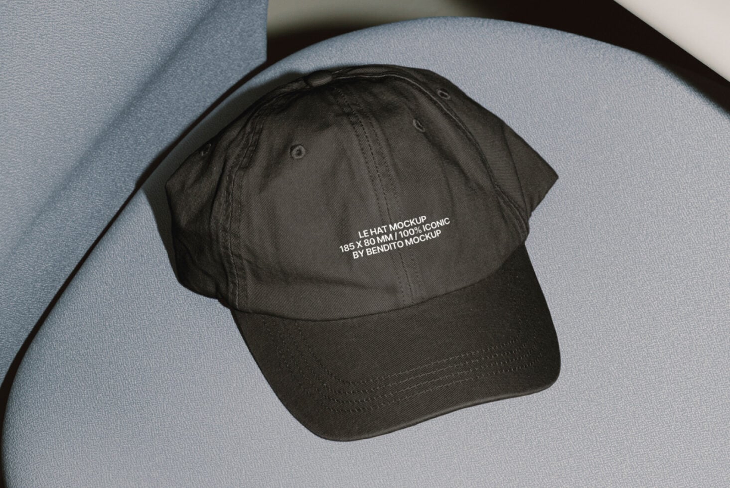 Black cap with small text print resting on curved blue geometric backdrop
