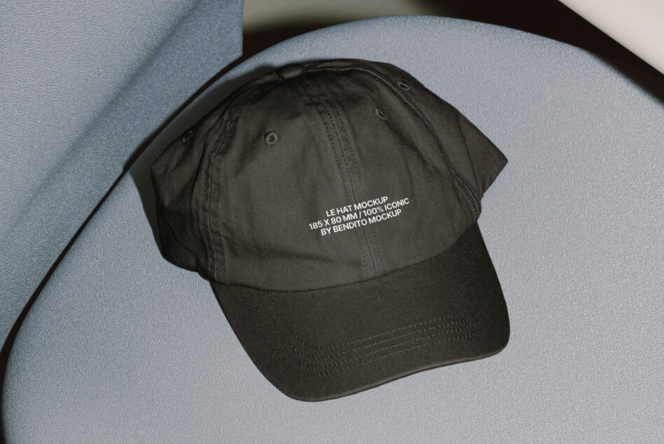 Black cap with small text print resting on curved blue geometric backdrop
