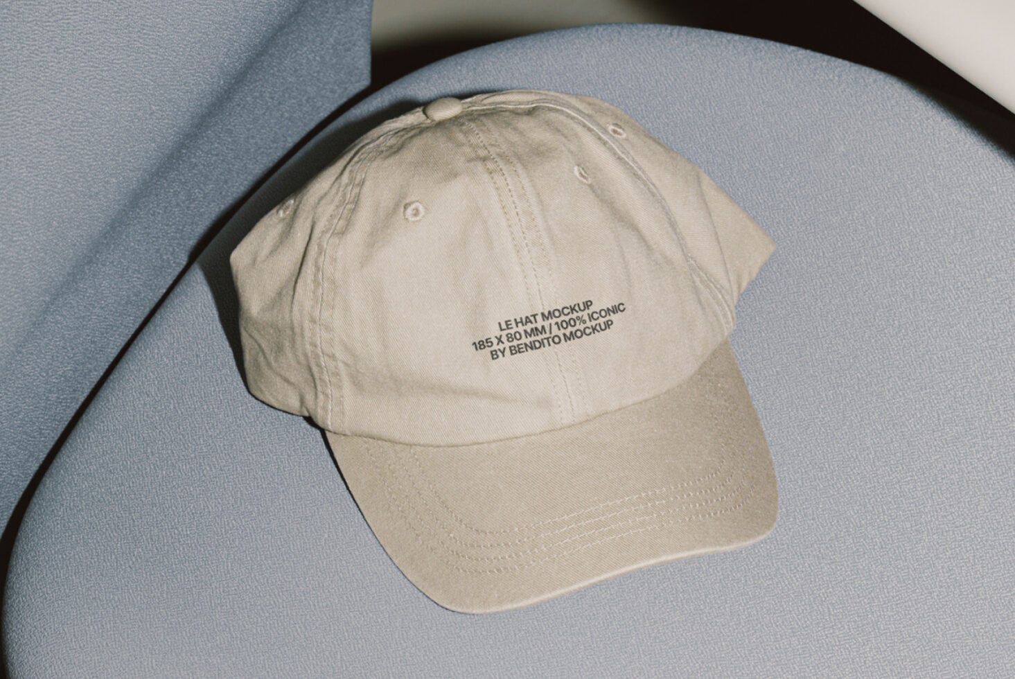 Beige cap with embroidered branding on blue curved architectural surface