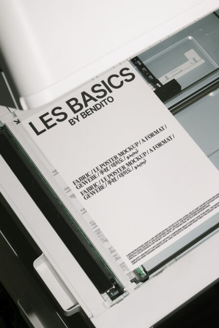 Printer scanning a mockup poster. Black text on white paper labeled Les Basics by Bendito. Perfect for designers. Keywords: Mockup, Poster, Design.