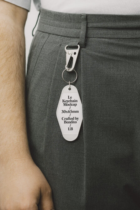 Vintage motel keychain in white attached to gray trousers via carabiner