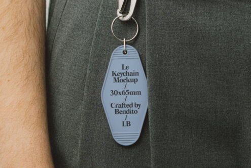 Keychain mockup featuring a blue tag, 30x65mm, dangling from fabric. Ideal for showcasing designs. Keywords: keychain mockup, design template.