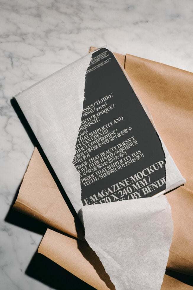 Elegant magazine mockup on marble surface partially wrapped in paper displaying typography. Ideal for showcasing editorial designs to graphic designers.