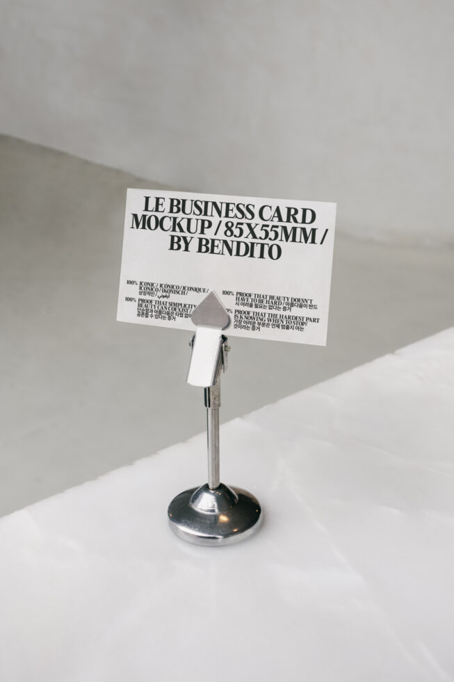 White business card mockup in metal stand with multilingual typography on minimal background