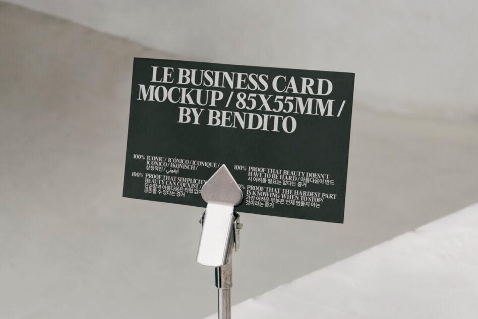 Dark green business card mockup on desk clip with white text, languages, clean minimalist setup