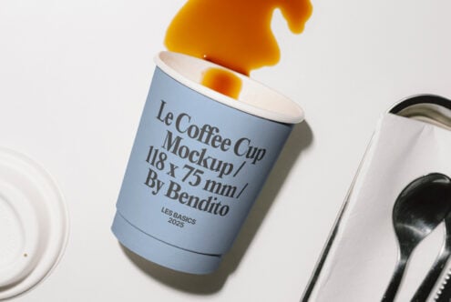 Le Coffee Cup Mockup showcasing a tilted blue disposable cup spilling coffee. Ideal for graphic designers seeking creative mockup templates in 2025.