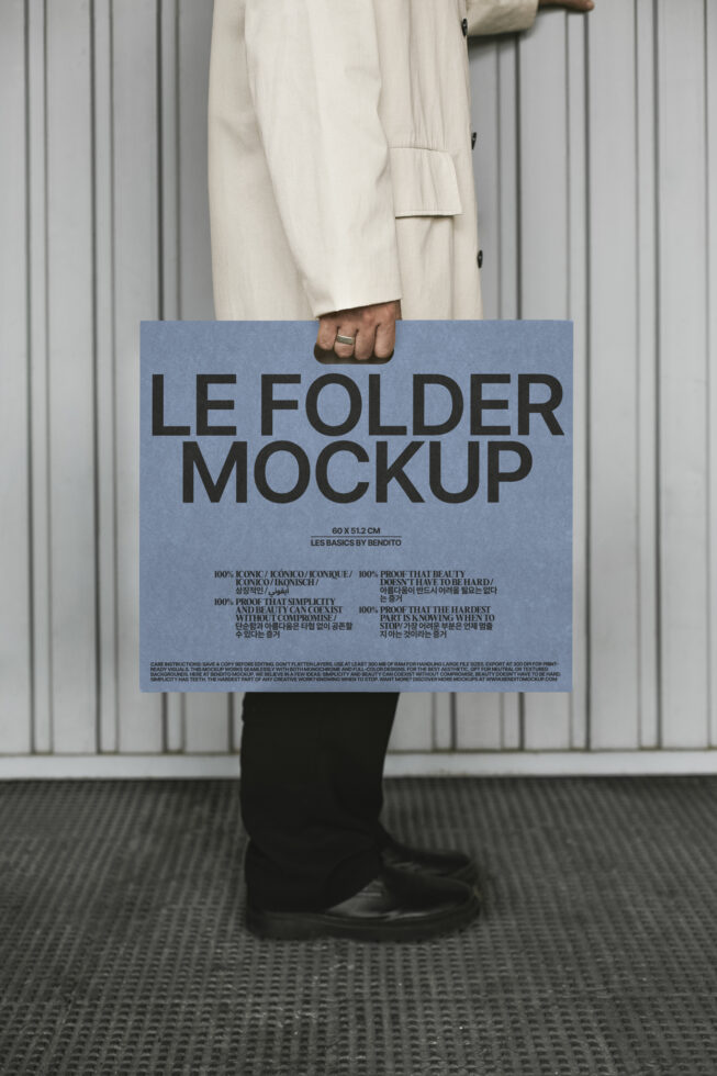 Person in beige coat holds large blue folder mockup against gray background. Design asset for designers. Template for branding presentations.