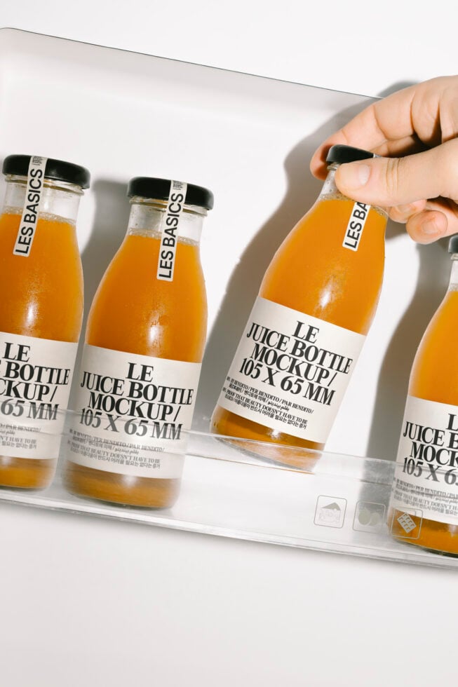 Four juice bottles with mockup labels in a hand display. Perfect for branding design showcase. Keywords: juice bottle mockup, branding, design template.