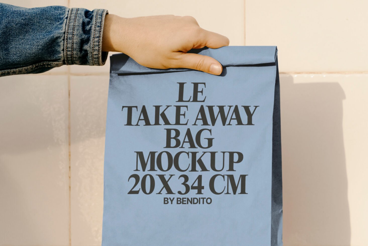 Blue paper take away bag mockup held by hand. Text reads LE TAKE AWAY BAG MOCKUP 20x34 CM. Ideal for packaging design, product showcase, branding.