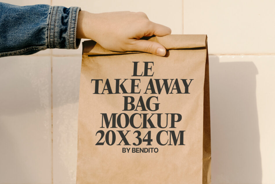 Hand gripping kraft paper takeaway bag with Le Takeaway Bag Mockup branding by Bendito