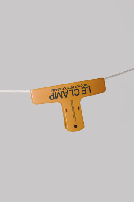 Mustard yellow T-shaped price tag suspended on string over neutral backdrop