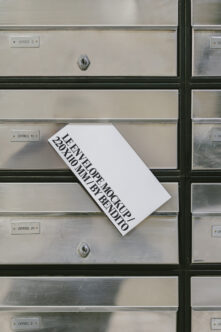 White business card mockup angled on brushed metal mailbox surface