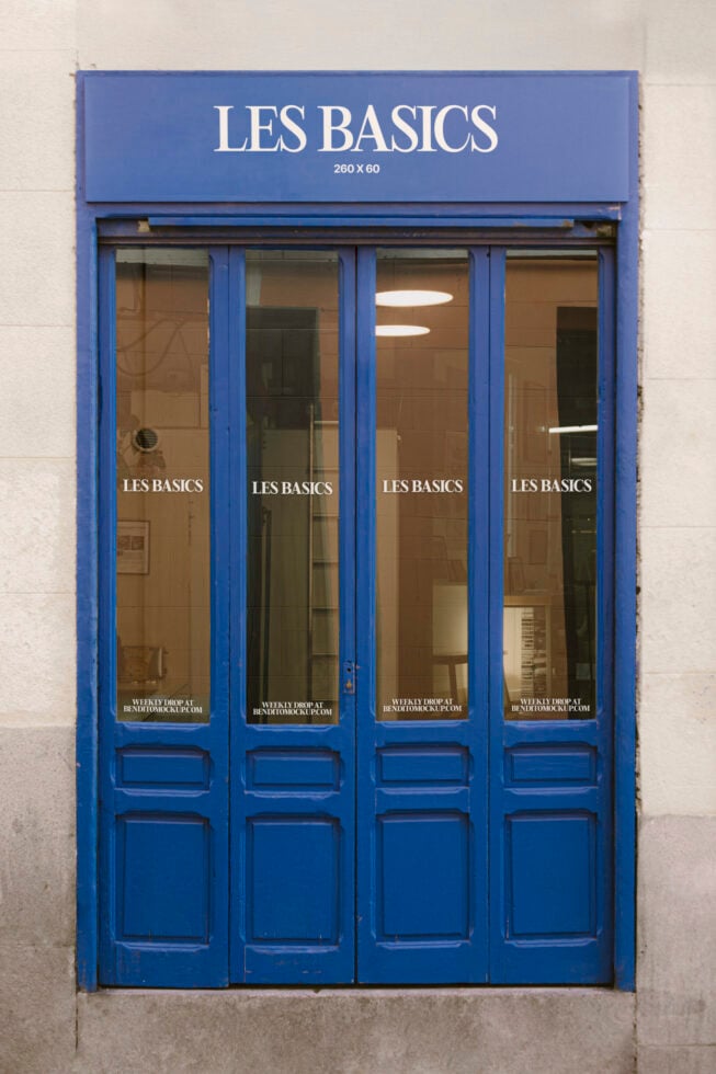 Blue shopfront with glass doors displays Les Basics signage. Ideal storefront mockup for branding designers. Urban retail template.