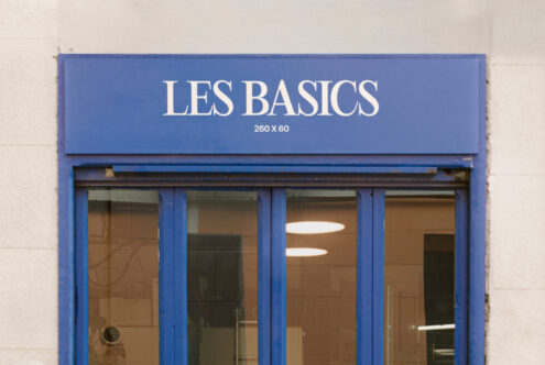 Storefront signage mockup with blue frame reading LES BASICS perfect for showcasing fonts and store branding design. Ideal for graphic designers.
