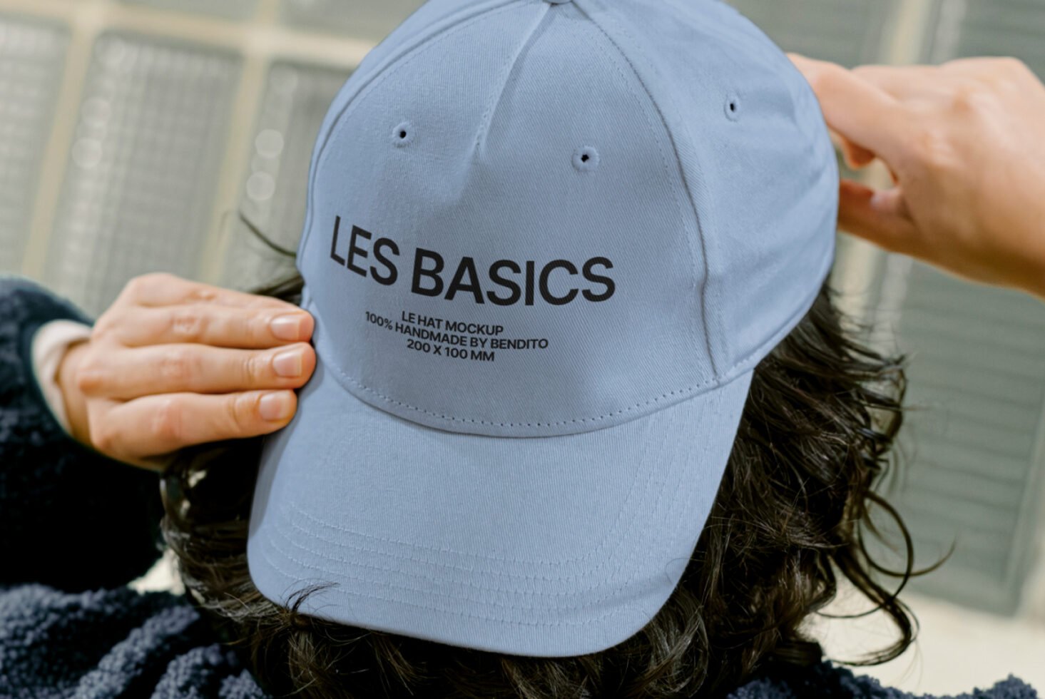 Close-up of a person adjusting a light blue cap with the text LES BASICS. Perfect for showcasing hat mockup templates and apparel design graphics.