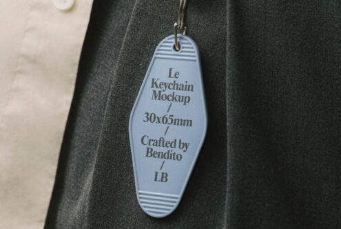 Keychain mockup with blue tag hanging on dark fabric showcasing design details 30x65mm for designers in need of customizable templates.