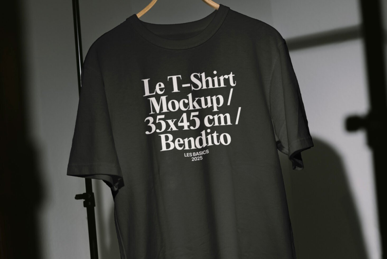 Black t-shirt mockup with white text hanging on a hanger; customizable apparel template for designers; ideal for showcasing design work