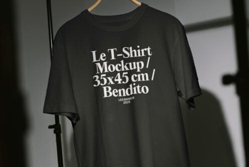 Black t-shirt mockup with white text hanging on a hanger; customizable apparel template for designers; ideal for showcasing design work