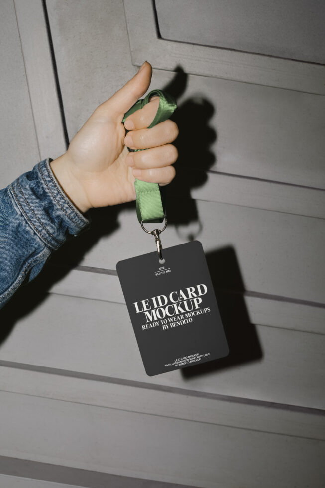 Hand holding an ID card mockup with a green lanyard against a concrete wall. Ideal for designers needing realistic identity card presentation templates.