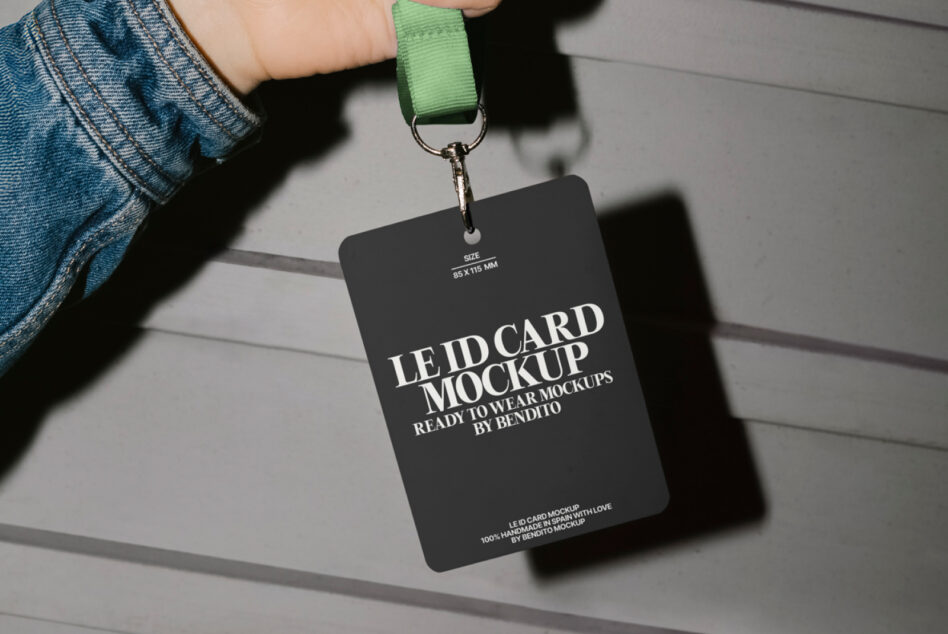 Hand holding black ID badge on green lanyard against concrete wall