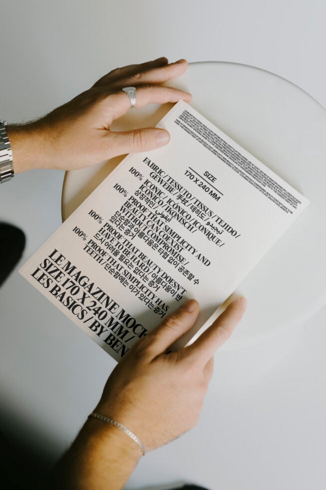 Person holding a minimalist magazine mockup featuring bold fonts and typography on a neutral background. Ideal for design and print templates.