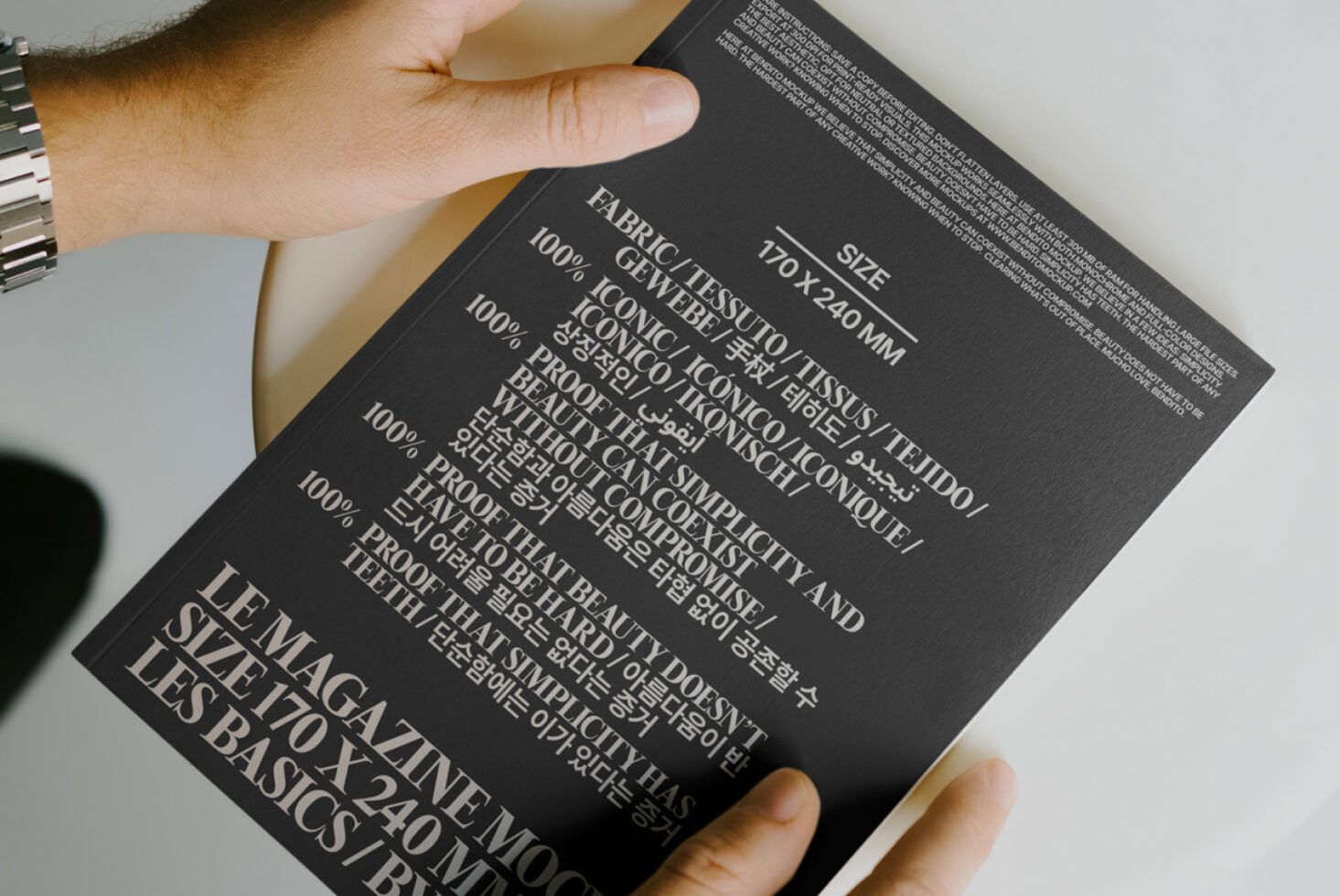 Person holding a black booklet with multilingual typography in white. Design template, mockup for showcasing fonts, graphic layout, editorial design.